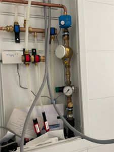 Fotografi av en gassmåler og tilhørende rørledninger og ventiler i en teknisk skuff.