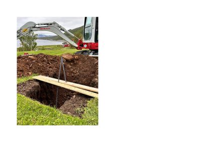 Fotografi av en graving med en Takeuchi-graver, en utgravd hull og en plank som strekker seg over hullkanten.