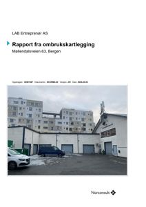 Fotografi av en industriell eller lagerbygning med hvite fasader og garasjedører, sett fra bakre side med bilplassering foran.