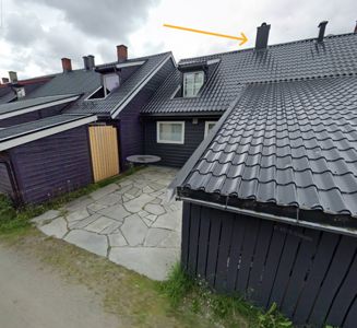 Fotografi av en rekkehusbebyggelse med fokus på takkonstruksjon, takfliser, skorsteiner og en steinlagt hagevei.