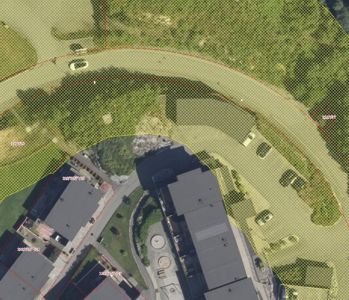 Flyfoto eller satellittbilde av et område med bygninger, veier og grøntområder, overlagret med digitale areal- og grensemarkeringer.