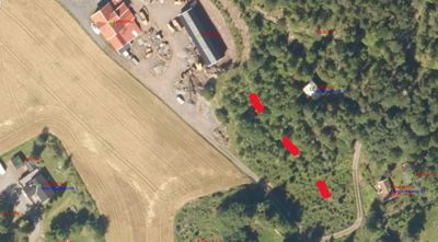 Flyfoto eller satellittbilde av et område med skog, en åker og flere bygninger, med overlagte digitale merknader og koordinater.