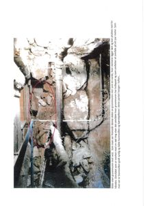 Fotografi av en grunnmur mot vest med synlig steinmur, bærebjelker og bunnsvill. Bildet viser et område hvor grunnmuren har kollapset.