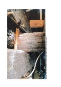 Fotografi som viser en kiler som er slått inn mellom et gulvbjelke og en stolpe i første etasje.