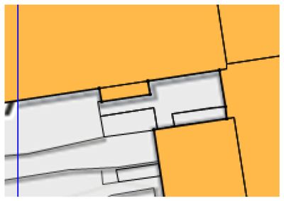 Dette er en detalj fra en situasjonsplan (tomteplan). Den viser hvordan bygningene (grå) er plassert i forhold til tomtegrensene (gult) og veier (svarte linjer).