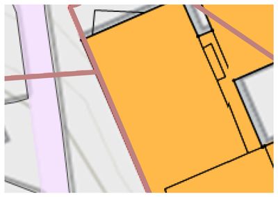 Et detaljutsnitt fra en situasjonsplan som viser tomtens grenser (røde linjer), bygningers plassering (svarte konturer) og muligens vegger eller bebyggelse i nærheten.