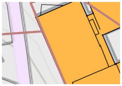 En detalj fra en situasjonsplan som viser et gult farget område (sannsynligvis bygning eller bebyggelse) i forhold til grå områder (vei/vegnett).