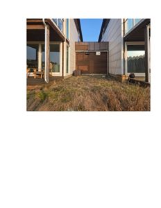 Fotografi av en tomme bakgård mellom to moderne bolighus.