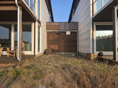 Fotografi av en bygning sett fra bakgård eller sidehage, som viser fasade, terrasse og omgivelser.