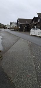 Fotografi av en vei og nabolag med flere hus i bakgrunnen.