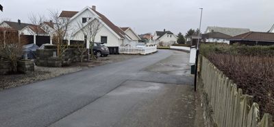 Fotografi av en nybygd eller ferdigstilt boligstrøk med asfalterte veier, garasjer og hekker.