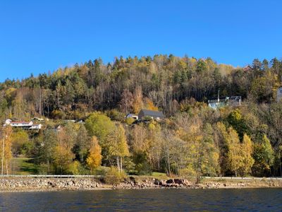 Fotografi av et landskap med hus på en skråning ved vann.