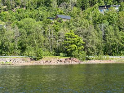 Fotografi av en bygning på en skråning ved vannet.
