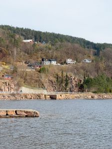 Fotografi av et kystlandskap med hus på en skråning.