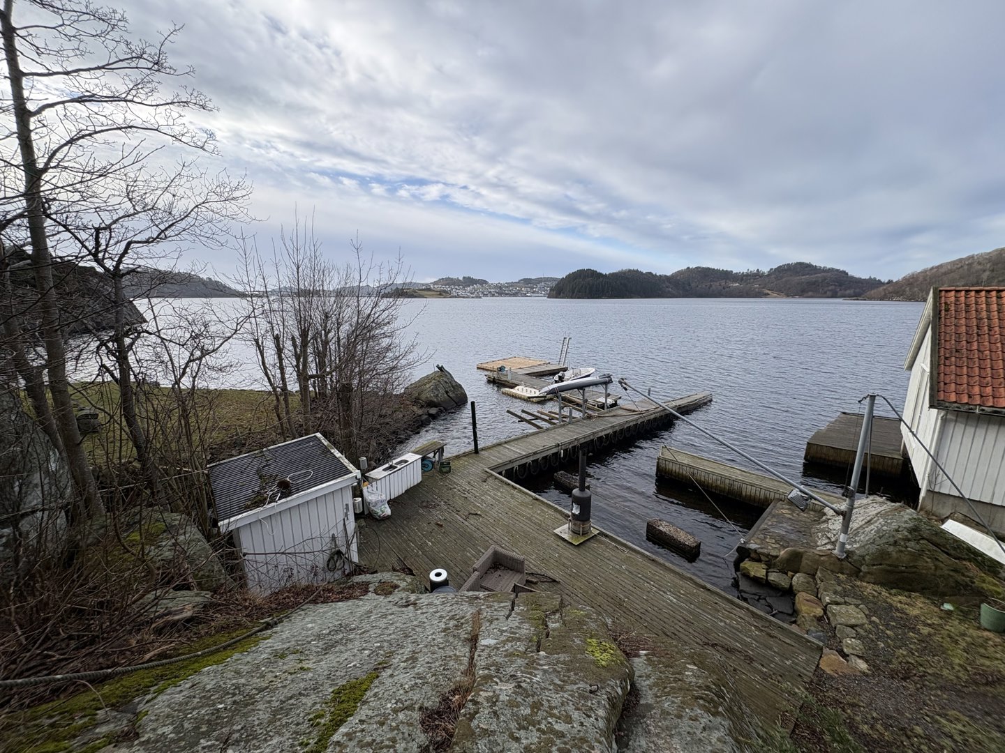 Fotografi av en brygge ved vannet med en bygning i forgrunnen.