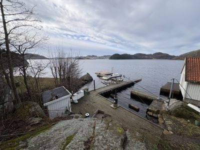 Fotografi av en brygge ved vannet med en bygning i forgrunnen.
