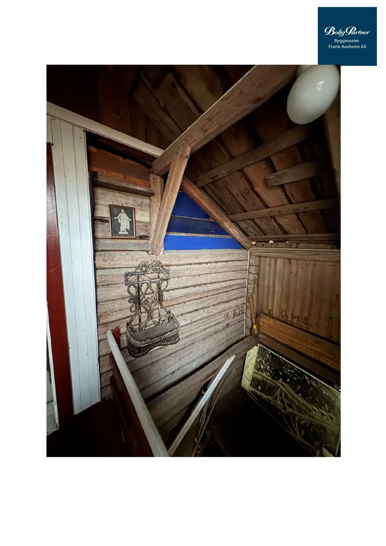 Fotografi av en innvendig trapp i en gammel, tømmerbygning med synlig konstruksjon og dekorasjoner.