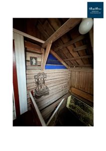 Fotografi av en innvendig trapp i en gammel, tømmerbygning med synlig konstruksjon og dekorasjoner.