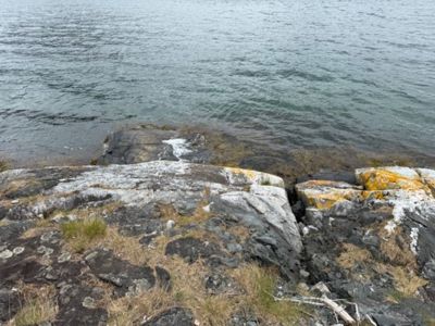 Fotografi av en kystlinje med klipper og vann.