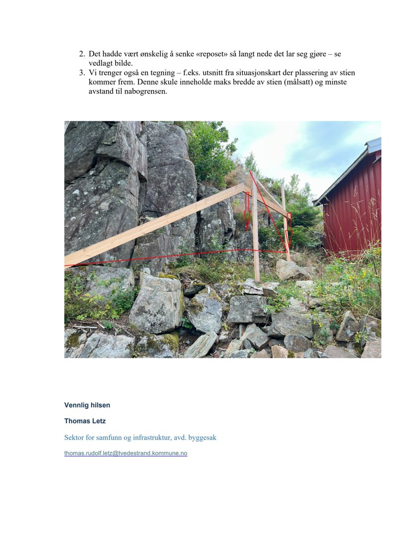 Fotografi av en steinmur eller steinblokk som er satt opp i terreng, med en rød bygning i bakgrunnen. Bildet illustrerer et fysisk element i byggesaken.