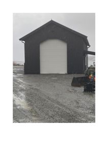 Fotografi av en mørk bygning med hvit port sett fra utsiden.