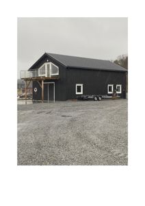 Fotografi av en ferdigbygd, svart bygning med etasjehus og balkong sett fra siden.