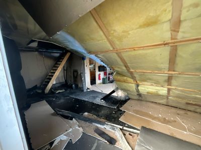 Fotografi av en skadet eller ødelagt innvendig del av et bygg, sannsynligvis et loft eller et underjordisk rom.