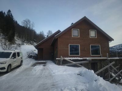 Fotografi av en ferdig eller nesten ferdig bygget hytte i en snødekket omgivelser.