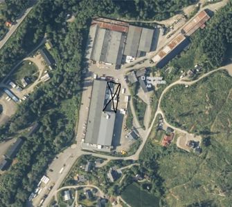 Satellittbilde (flyfoto) av et industriområde med flere bygninger, veier og skog. Bildet viser tomtens beliggenhet i forhold til omgivelser.