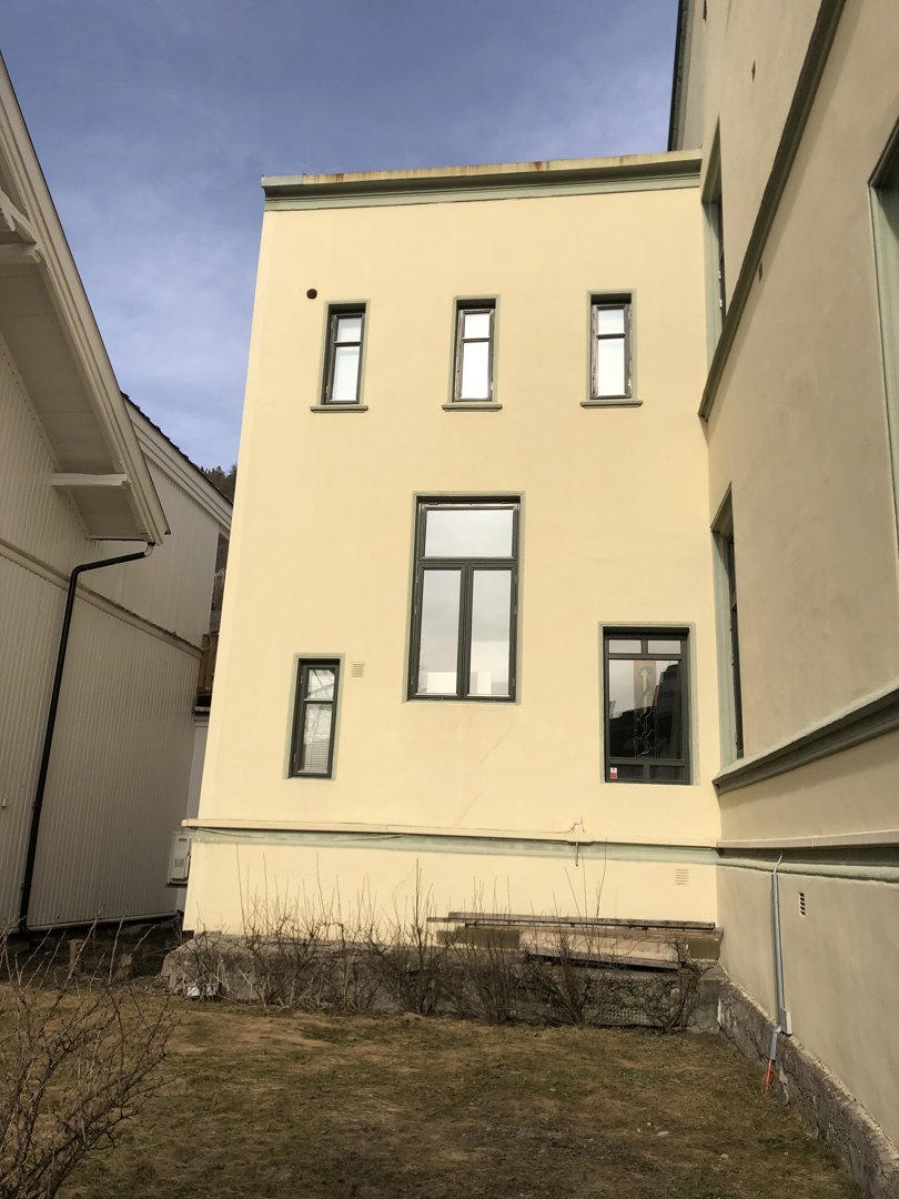 Fotografi av en gul bygning sett fra bakken mot himmelen.