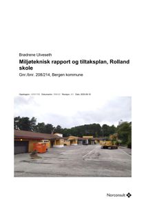 Fotografi av Rolland skole med gule bygninger, en gressbeplantet bakgrunn, en gullgraver og en oransje container på en asfaltert plass.