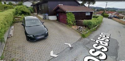 Fotografi av en bolig med garasje, kjøretøy og omgivelser.