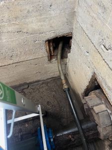 Fotografi av en utvendig vegg med en åpen uttak for en rørledning (sannsynligvis gass eller vann) og en trapp i forgrunnen.