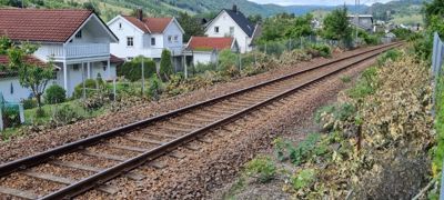 Fotografi som viser en jernbanespor som går forbi en rekke hus i et boligområde.