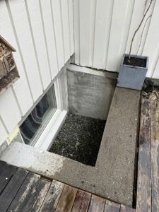 Fotografi av en utvendig vegg med vindusutgang, en betongkonstruksjon og en trapp opp til et dekk.