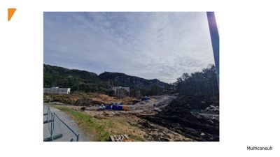 Fotografi av et byggefelt med terrengarbeider, en vei og bygninger i bakgrunnen.