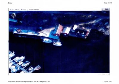 Flyfoto eller kartutsnitt som viser en bygning ved vannkanten, muligens en båthavn eller kai.