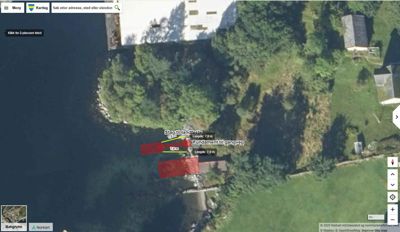 Satellittbilde (flyfoto) av et område med vann, vegetasjon og en bygning, med overlagte digitale tegninger som viser en planlagt gangveg og fundamenter.