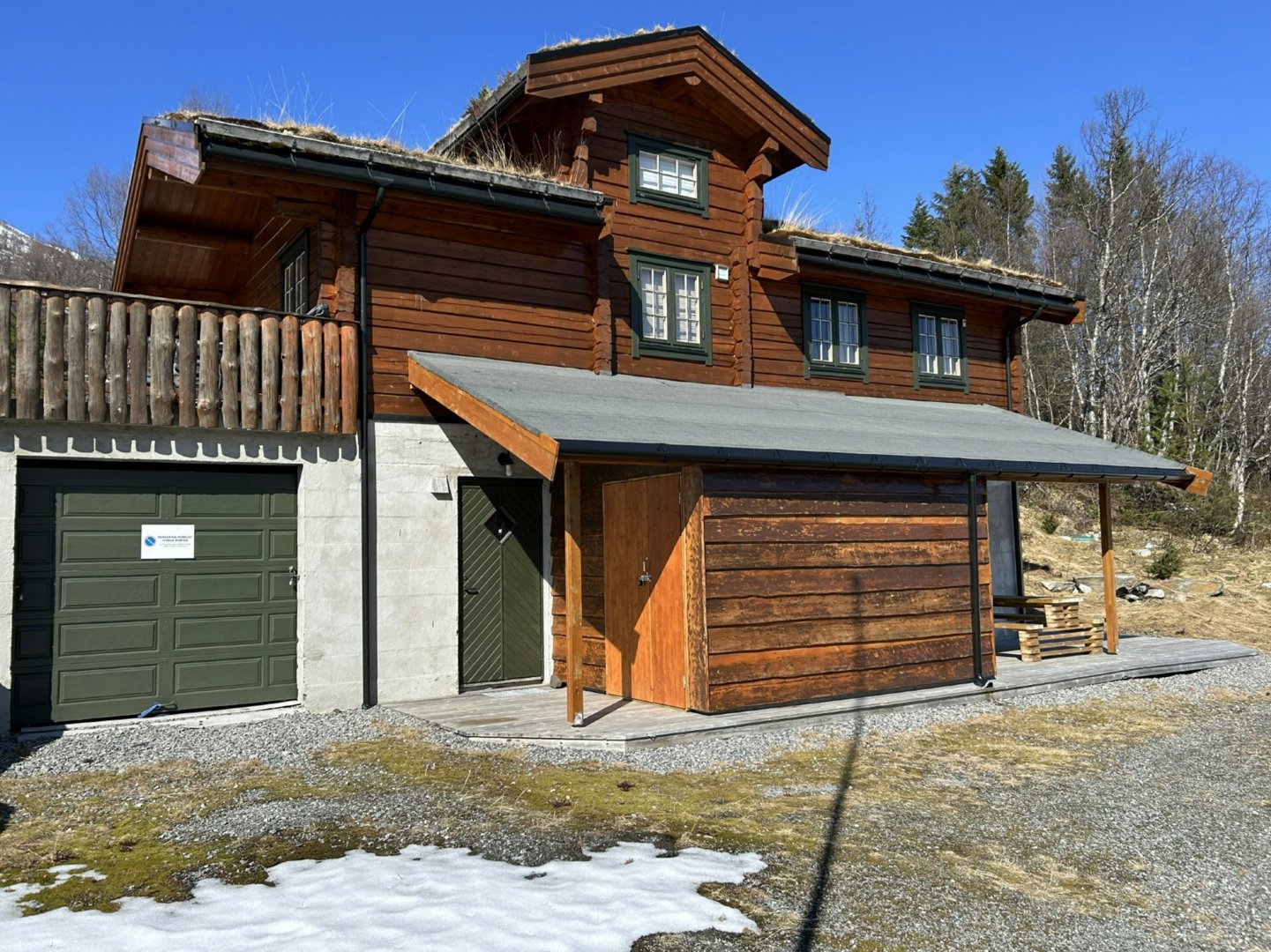 Fotografi av en ferdigbygd hytte med garasje og uthus.
