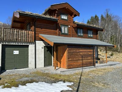 Fotografi av en ferdigbygd hytte med garasje og uthus.