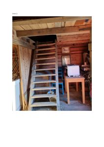 Fotografi av en trapp og et lite rom med trepanelvegger, sannsynligvis i en eldre bygning.