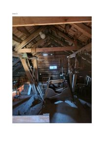 Fotografi av et gammelt, trekonstruert rom med takbjelker og møbler.