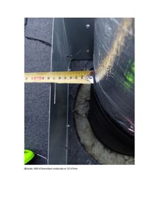 Fotografi av en måling på en bygning, sannsynligvis en skorstein eller ventilasjonssjakt, med en målebånd som viser avstand til brennbart materiale.