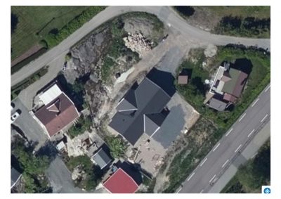 Luftfoto (satellittbilde) av en tomt med en bygning under oppføring, omgitt av naboer og veier.