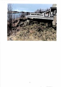 Fotografi av en bygning (eller del av en bygning) sett fra siden, med utsikt over vann og terreng.