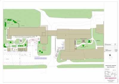 Situasjonsplan som viser bygningenes plassering i forhold til tomme, parkeringsplasser og omgivende terreng.