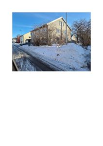 Fotografi av en fleretasjes bygning med snø på bakken og gaten.