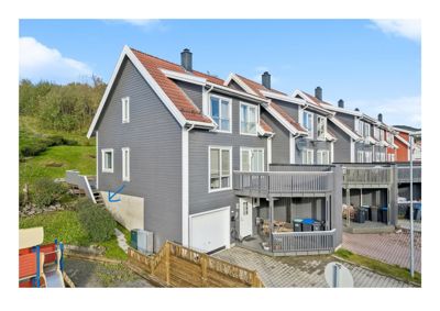 Fotografi av en rekkehusbebyggelse med grå fasader og røde tak, sett fra siden.