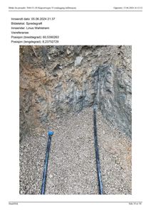 Fotografi av et spredegrøft med to blå markører i gruslag og jordvegg.