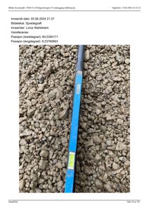 Fotografi av et spredegrøft med en blå målestokk eller nivå i grus.